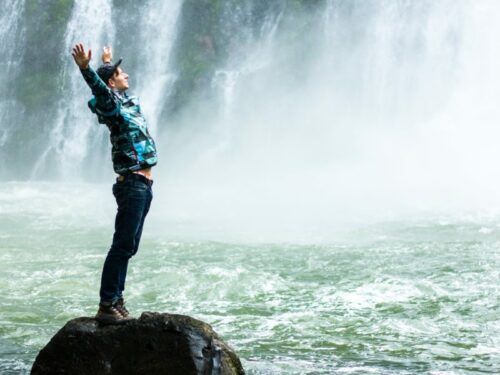 Person stretching by the Water in front of a waterfall - Image